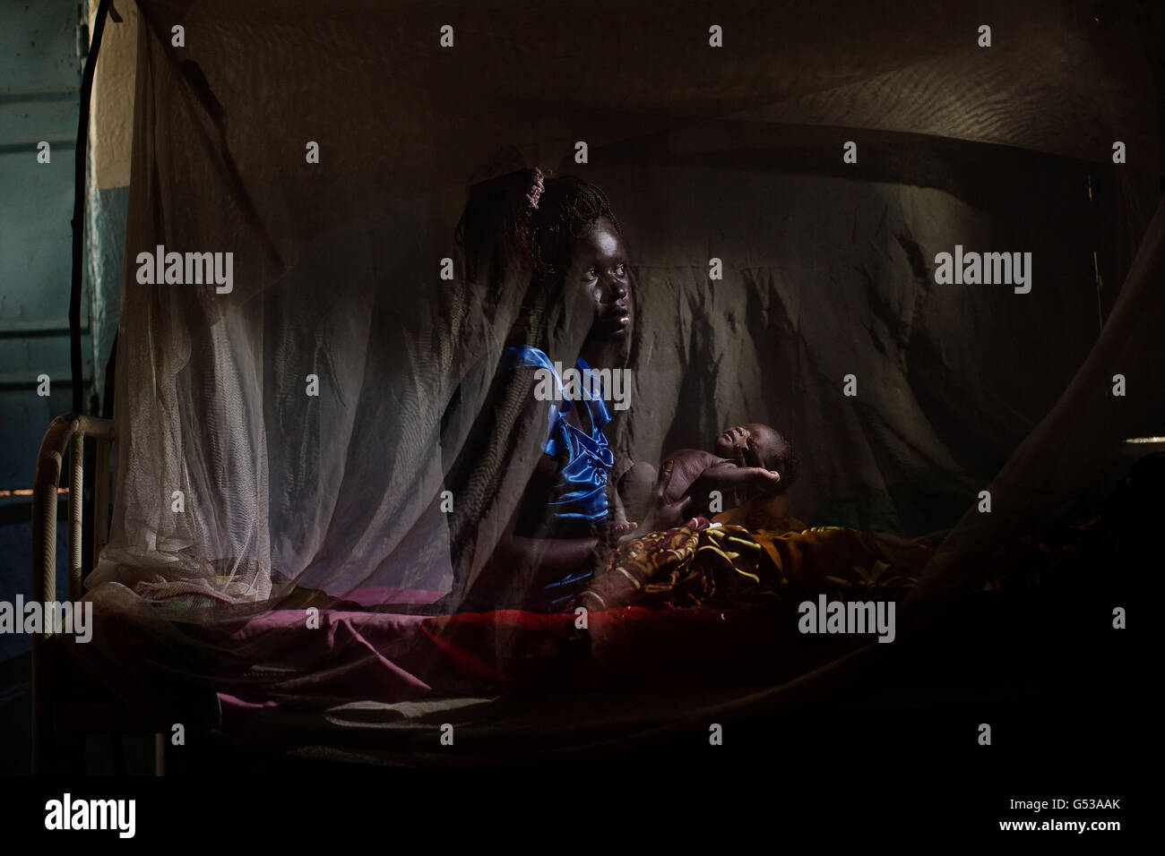 A woman holds her new born baby inside her mosquito net after she gave birth in the Goal clinic in Balliet,a village along the Sobat River in the Greater Upper Nile region of northeastern South Sudan, Africa.The region recently suffered from serious inter tribal fighting resulting in thousands of people forced into internally displaced people (IDP) camps.Goal ,the Irish aid agency working in Sudan since 1985 has been at the forefront of providing aid and shelter to Sudanese people affected by war and poverty. Stock Photo