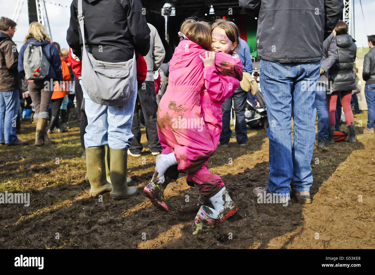 Florence (surname not given), 8, rescues her little sister Charlotte, 6, from Hampshire, as she looses her Wellington boot in the sticky mud in the crowd at One Fest music festival, near Marlborough in Wiltshire. Stock Photo