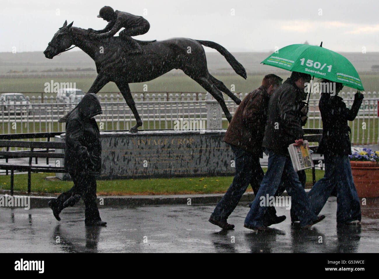 Racegoers shelter from the heavy rain during the Big Bad Bob Gladness Stakes Day at Curragh Racecourse, Co. Kildare, Ireland. Stock Photo