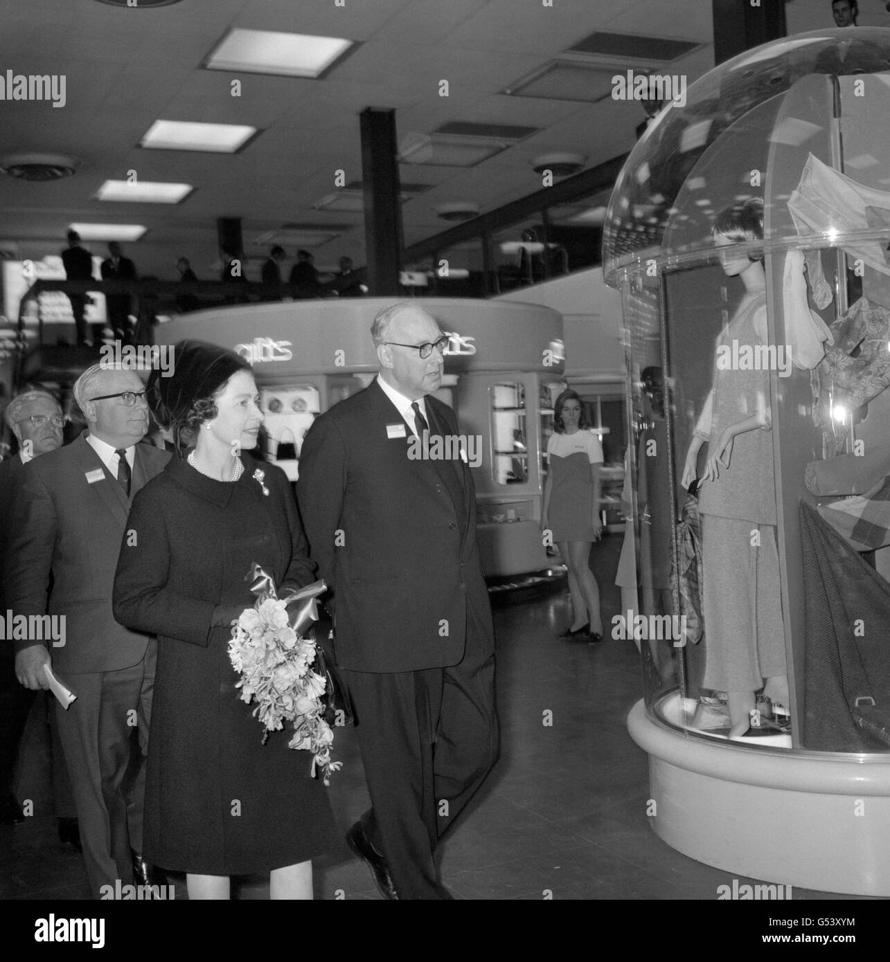 The Queen with Peter Masefield, Chairman of the British Airports Authority, views a window display in the shopping area as she toured the new Cargo Area and Terminal One at Heathrow Airport, London. Stock Photo