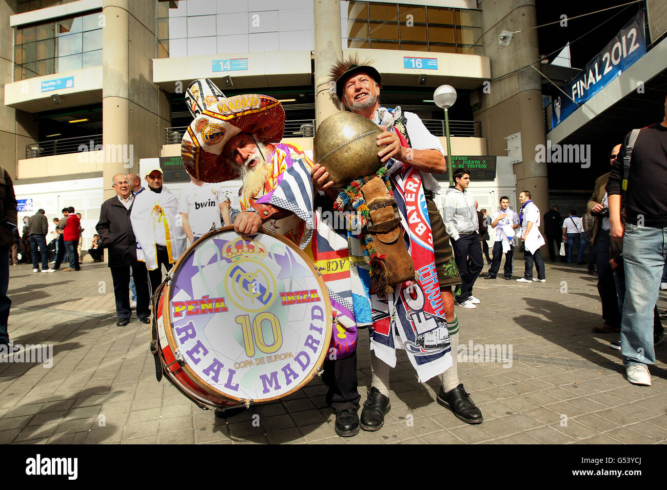 A Bayern Munich fan rings a traditional cow bell alongside a Real Madrid fan playing the drum outside the Santiago Bernabeu stadium before the match Stock Photo