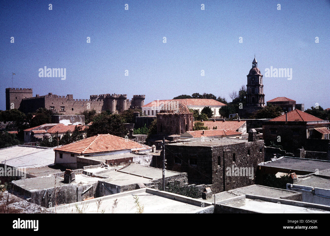RHODES: Rooftops in the old city of Rhodes. In the distance is Palace of the Grand Masters, built by the Knight Hospitallers (Order of St. John). Rhodes was the most important base for the Order until the knights' expulsion by the Turkish Sultan, Suleiman the Magnificent, in 1522. The castle was heavily restored during the Italian occupation of the Dodecanese in the early 20th century. Stock Photo