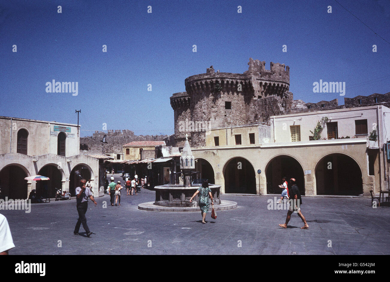 RHODES: Hippokrateous Square in the old city of Rhodes. In the background is marine gate of the fortifications built by the Knight Hospitallers (Order of St. John). Rhodes was the main base for the Order before the knights' expulsion by the Turkish Sultan Suleiman the Magnificent in 1522. Stock Photo