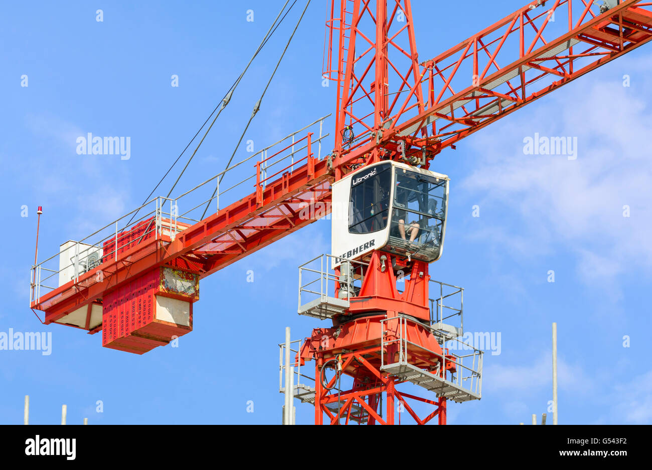 Liebherr Litronic red tower crane showing the crane driver in his cabin. Stock Photo
