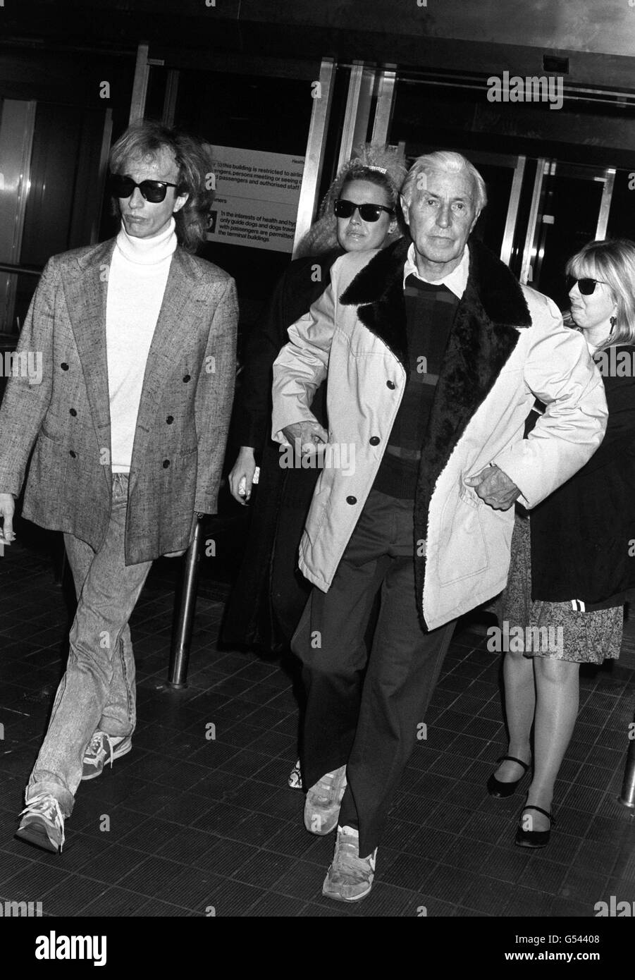 Robin Gibb of 'The Bee Gees', left, and his wife Dwina, centre, with his father Hughie Gibb and a family friend at Heathrow Airport, after he flew in from Los Angeles to be with his wife Barbara following the death of their youngest son Andy. Stock Photo