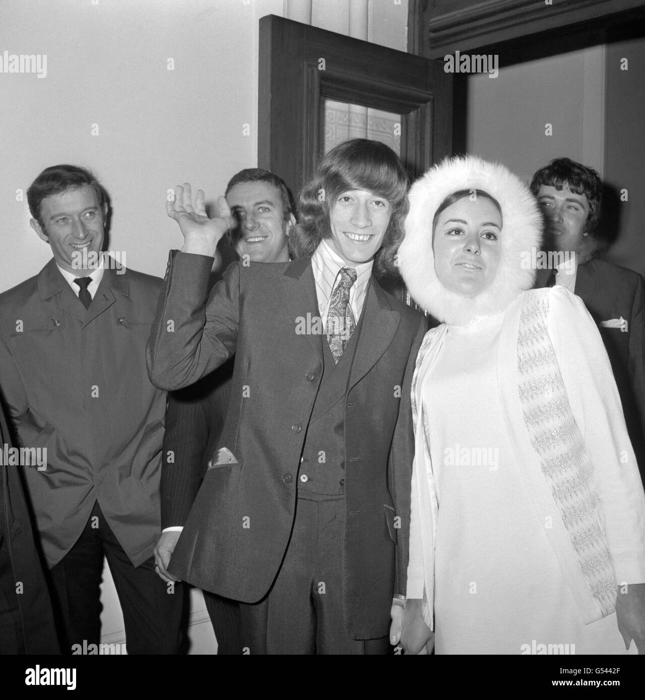 A wave from 19 year old Robin Gibb, member of the Bee Gees, as he leaves Caxton Hall register office, London, with his fur-bonneted bride after their wedding. She was 21 year old Molly Hullis, whom Mr Gibb met two years ago shortly after the Bee Gees came to the UK from Australia. Stock Photo