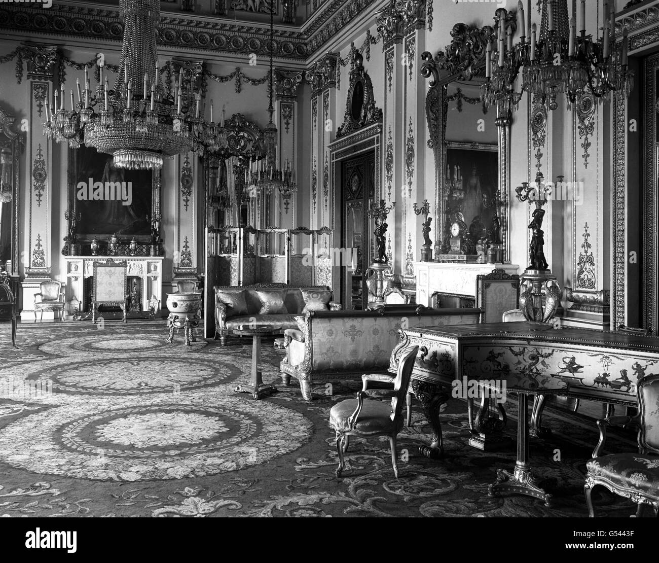 The White Drawing Room inside Buckingham Palace, showing its ornate design in white and gold. In the room can be seen some fine specimens of French and Regency furniture, handsome chandeliers, and its beautiful piano, giving a rich and satisfying appearance. Stock Photo