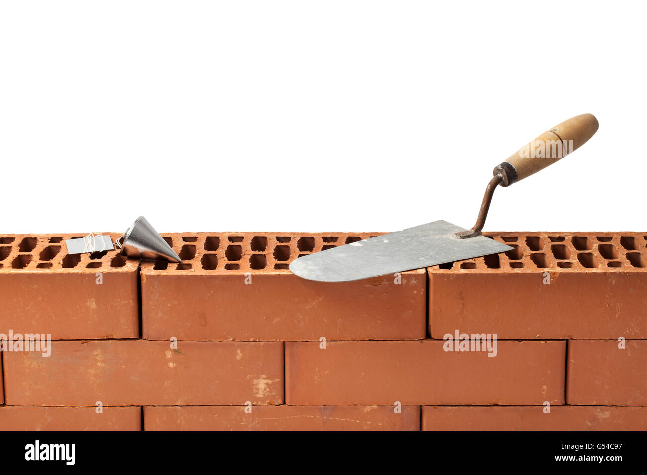 Construction tools trowel and plumb bob left on a new brickwork isolated on white. Stock Photo