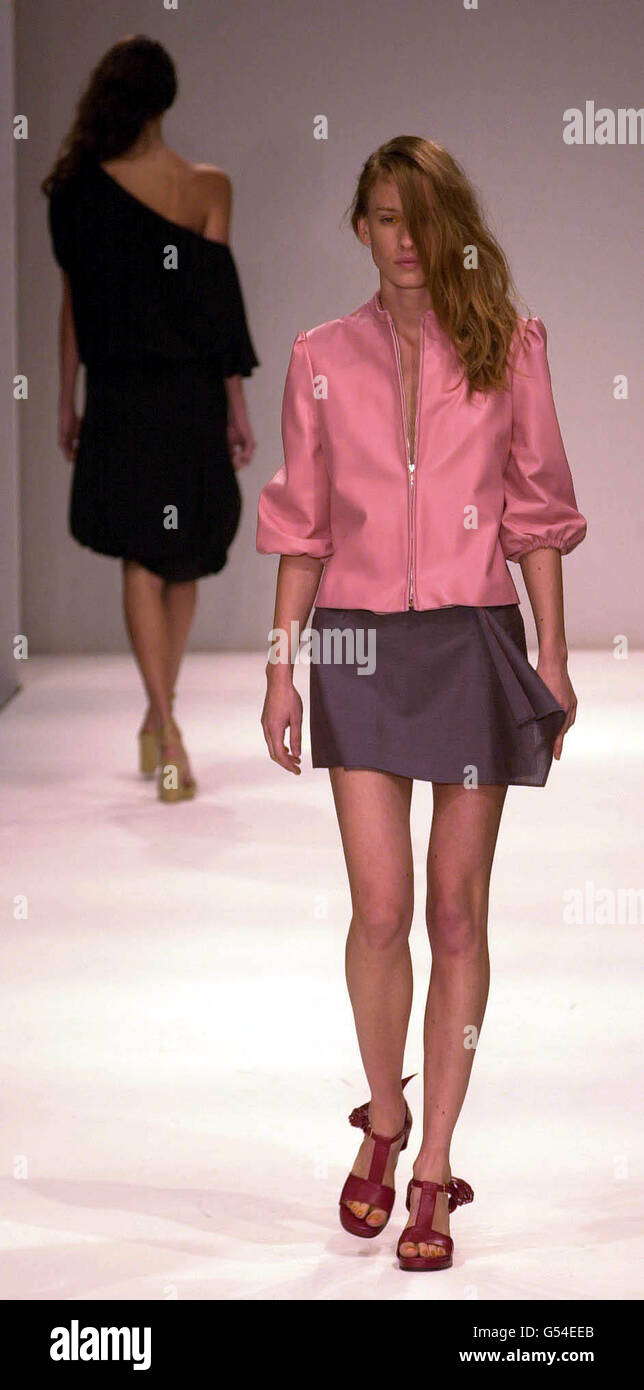 A model wears a wrap mini-skirt and pink leather zipped jacket with cropped blouson sleeves by Irish based designer John Rocha, at London Fashion Week. Stock Photo