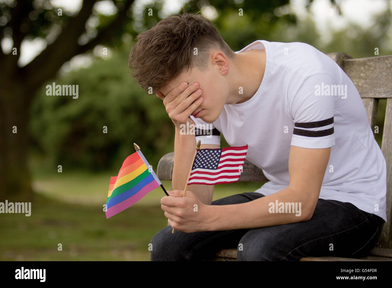 Depressed teenage boy with United States Flag and a Pride flag Stock Photo