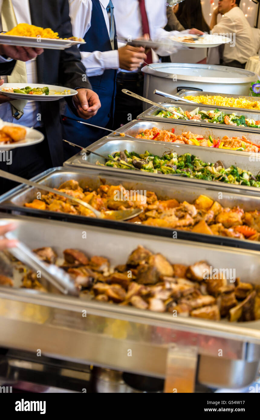 People help themselves to food at a self-service buffet at a party. Stock Photo