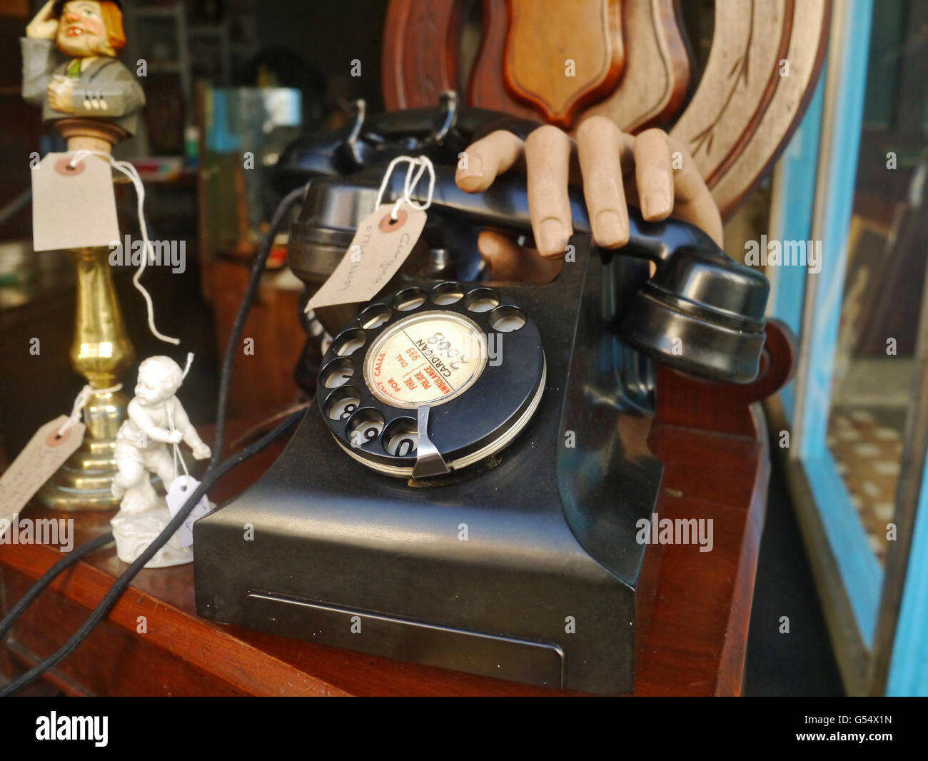 Old fashioned telephone with shop dummy hand antique shop window Stock Photo