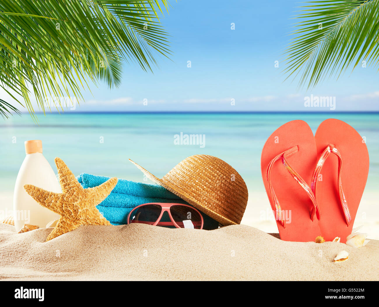 Summer accessories on sandy beach, blur sea on background. Summer exotic relaxation concept. Copyspace for text Stock Photo