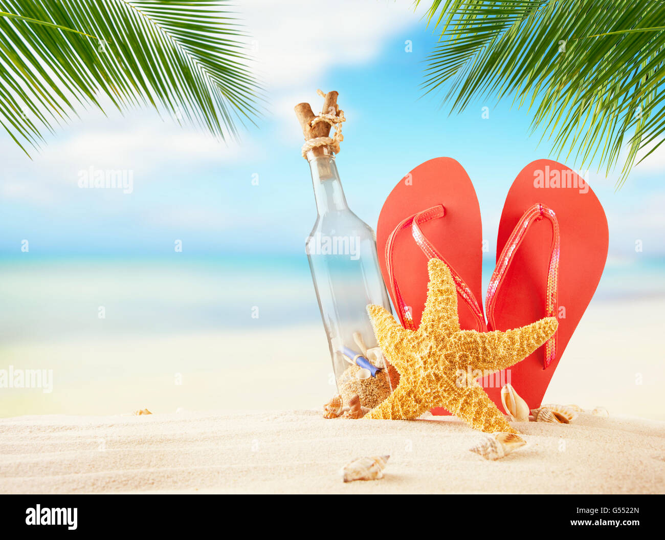 Empty glass and flipflops on beach, blur sea on background. Summer exotic relaxation concept. Copyspace for text Stock Photo