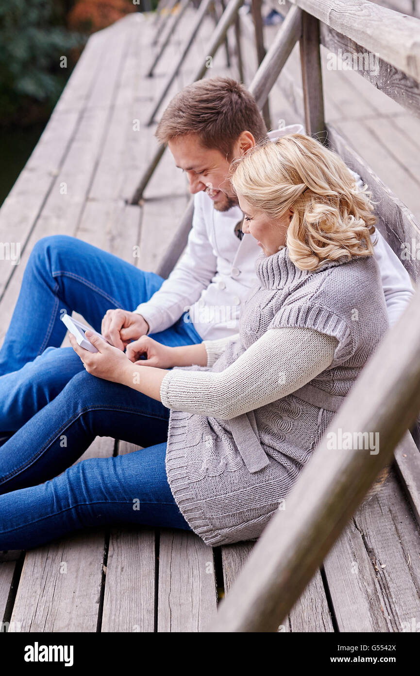 young couple happy husband and pregnant wife relaxing on a bench Stock Photo
