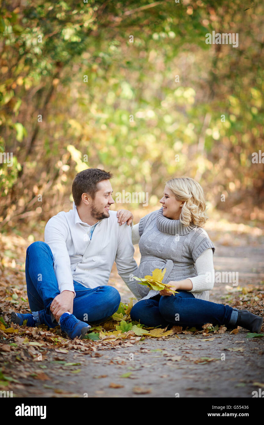 Husband and his pregnant wife relaxing in autumn park Stock Photo