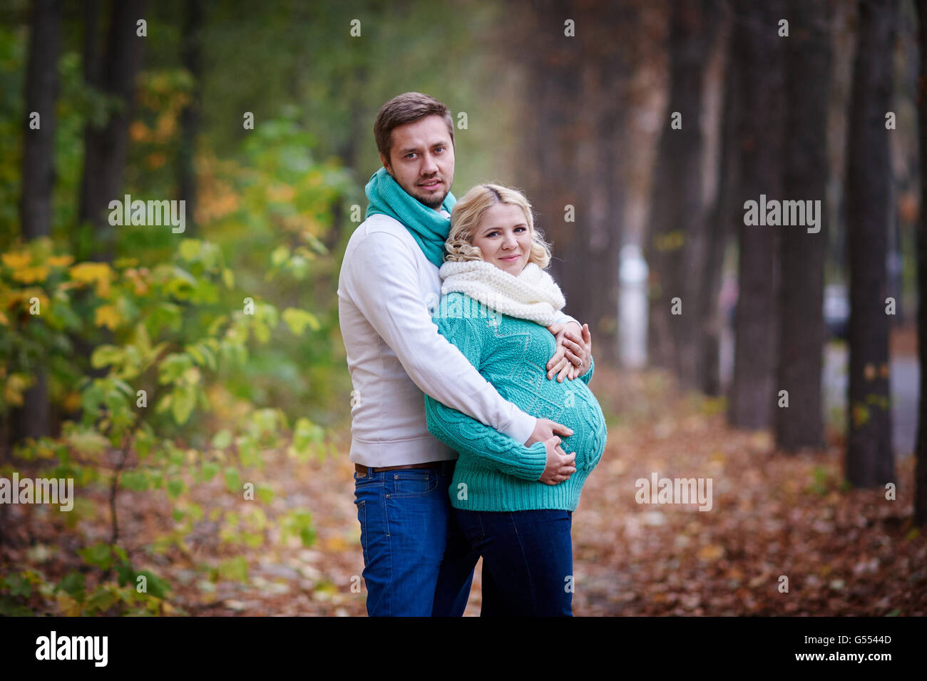 husband and pregnant wife are walking in autumn park Stock Photo