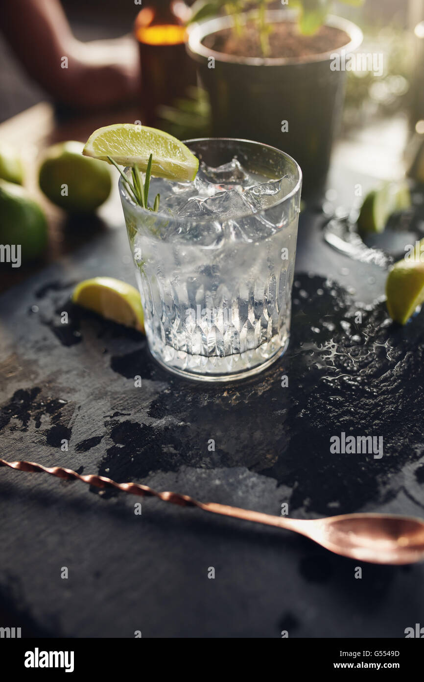 Glass of fresh cocktail drink with lemon slice and ice cubes on a black board. Stock Photo