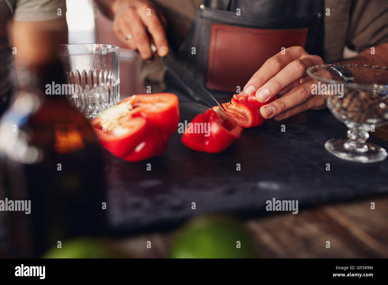Close up shot of bartender hands chopping red bell pepper on the cutting board. Experimenting with new cocktail ideas. Stock Photo