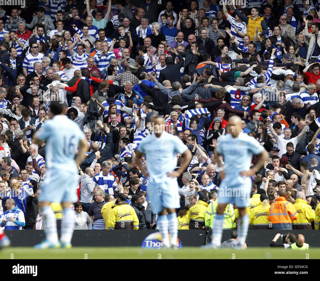 QPR fans do the Poznan celebration as Manchester City players appear dejected after QPR scored a second goal during the Barclays Premier League match at the Etihad Stadium, Manchester. Stock Photo
