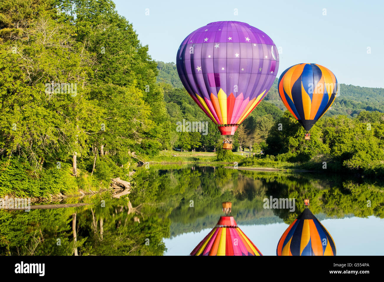 Hot air balloon taking off above river during Quechee hot air balloons festival with people in basket. Stock Photo