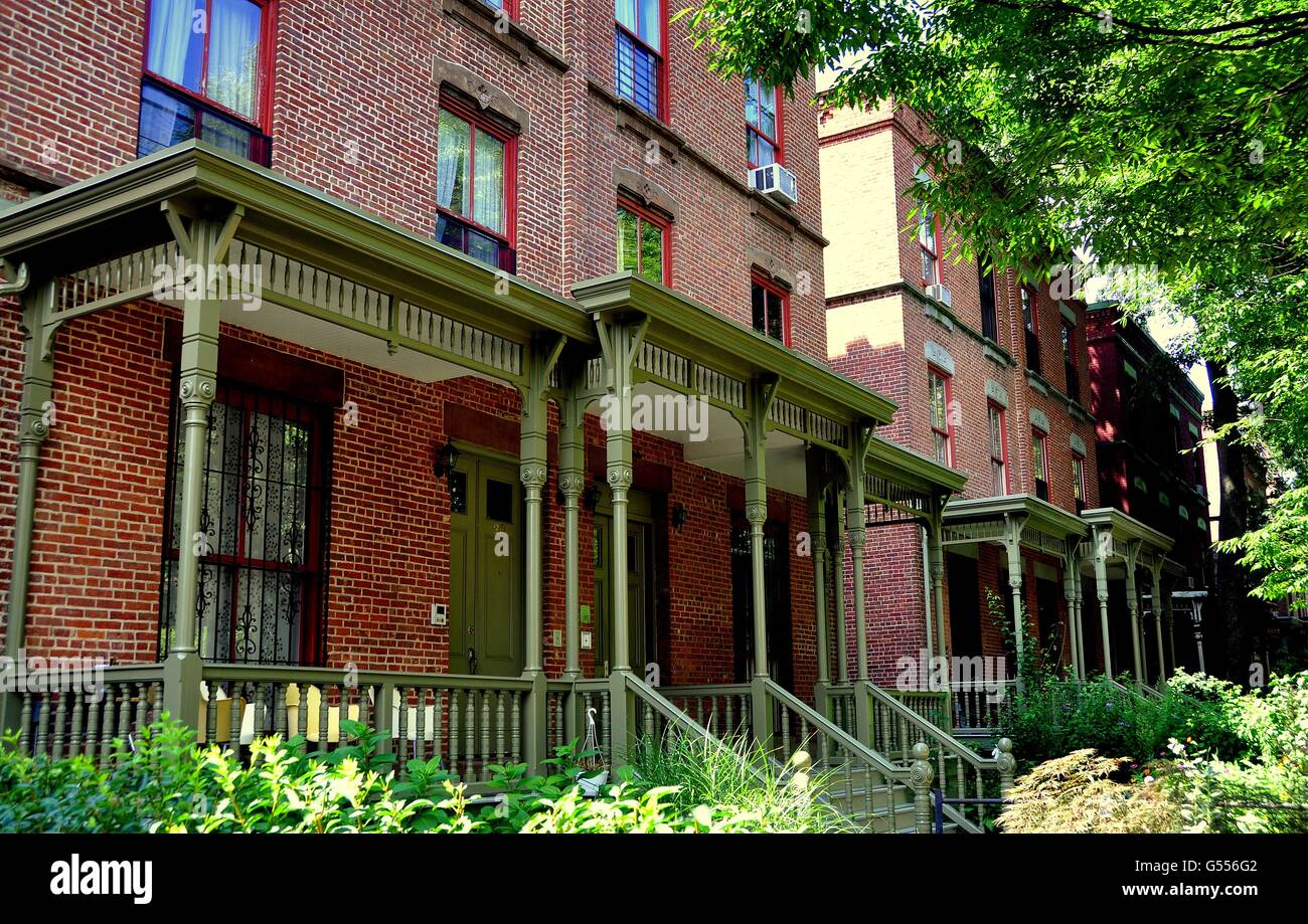 New York City:  Brick homes with wooden Victorian porches and gardens line Astor Row on West 130th Street in Harlem Stock Photo