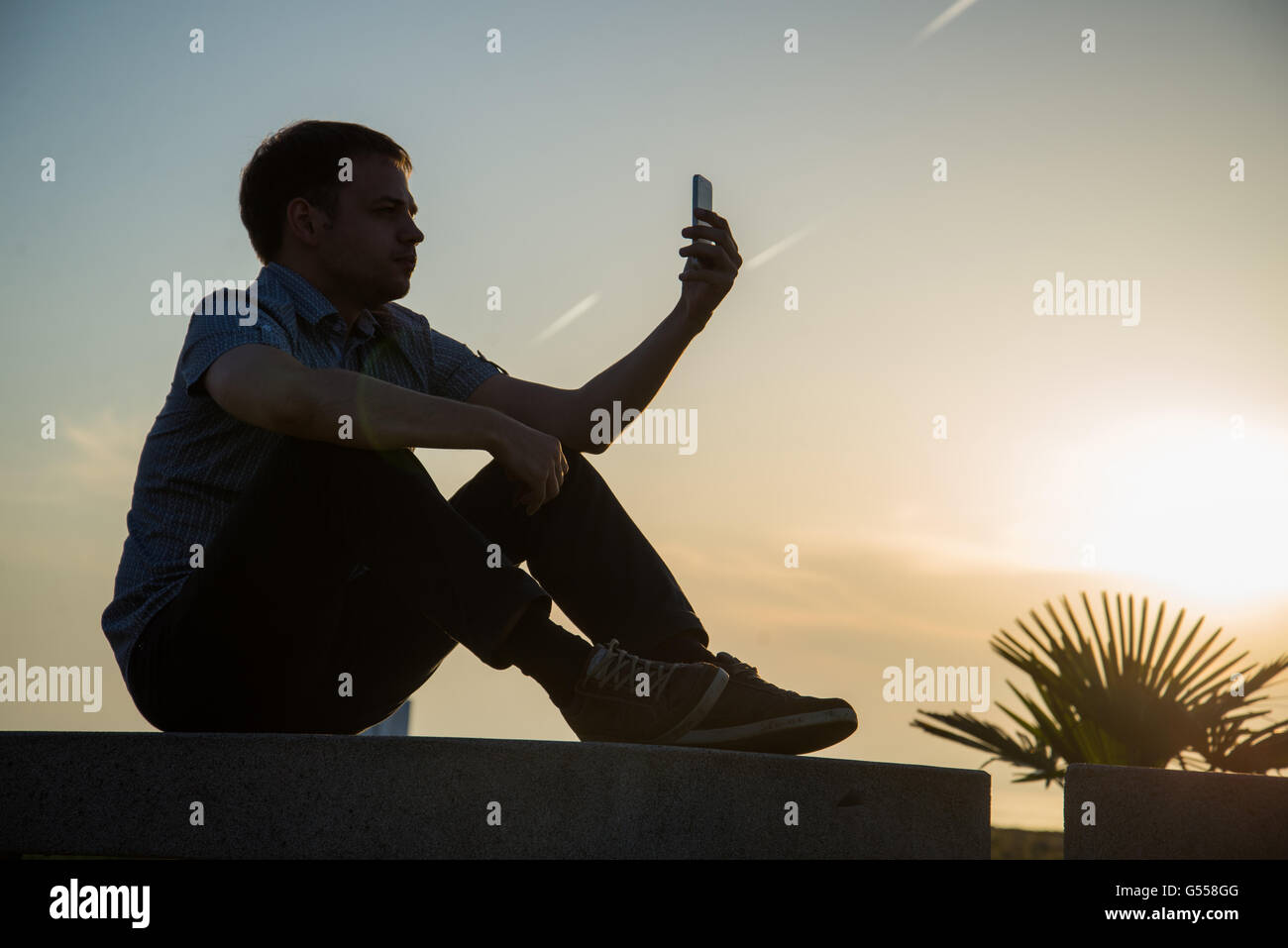 Young guy is watching photos on mobile phone what he took now during rest near sea with copy space background for your advertising text message or content Stock Photo