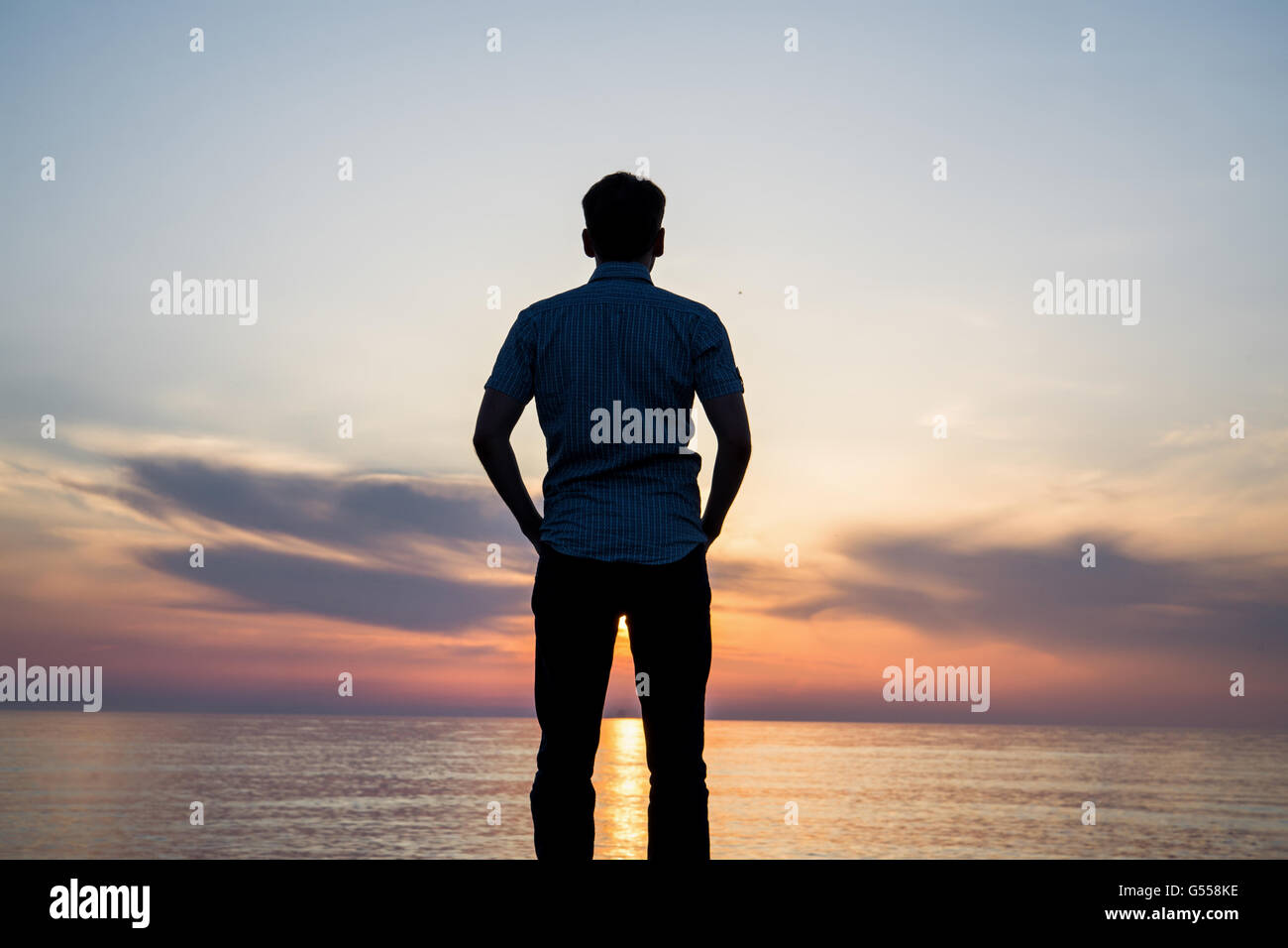 Silhouette of young man on the beach at sunset Stock Photo - Alamy