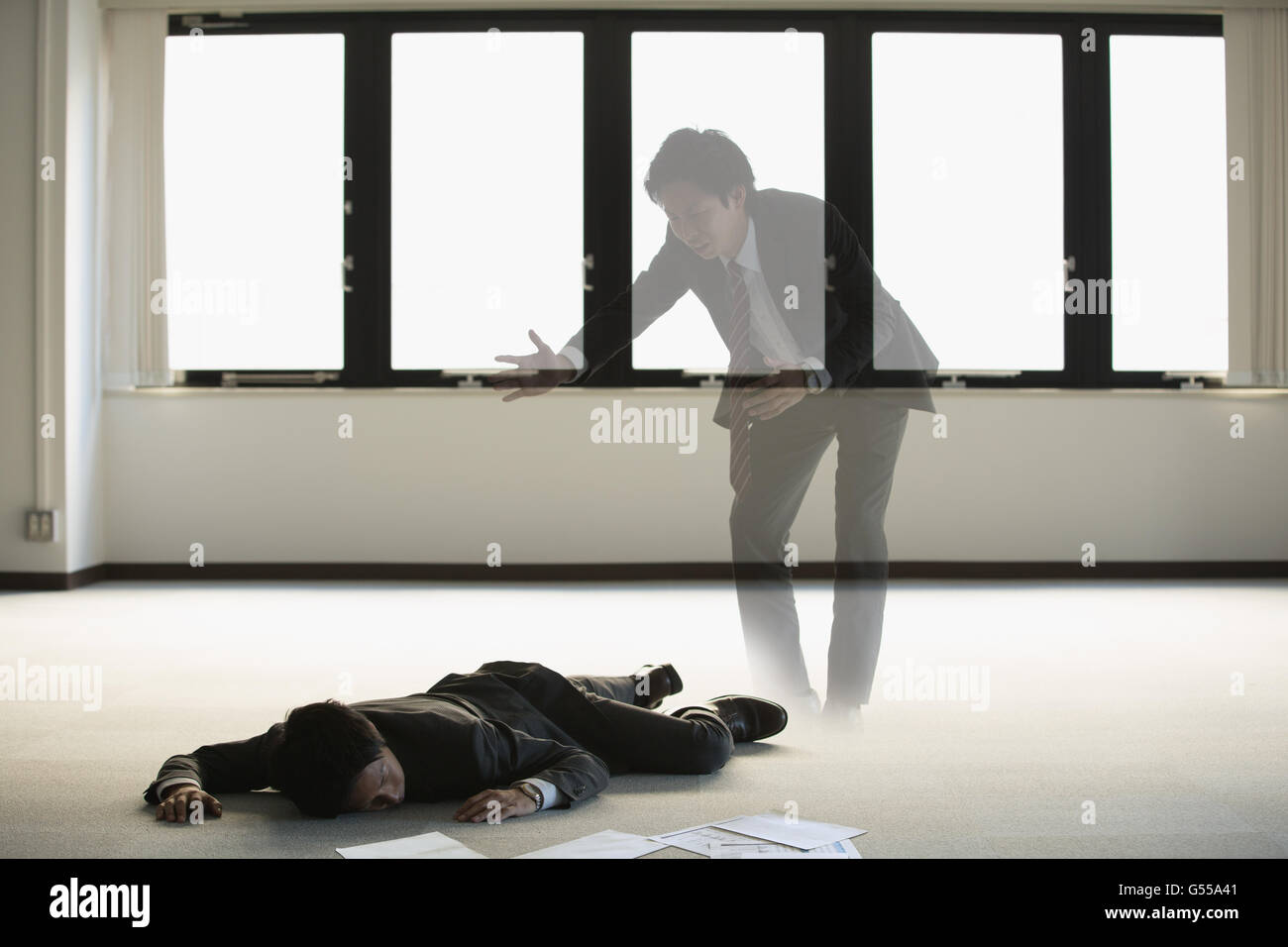 Young Japanese businessman dead on the floor of an empty office Stock Photo