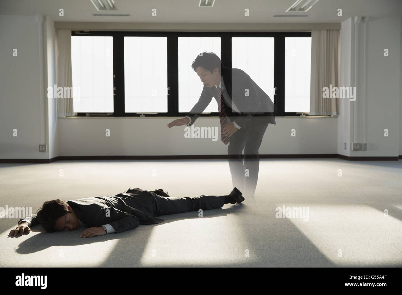 Young Japanese businessman dead on the floor of an empty office Stock Photo