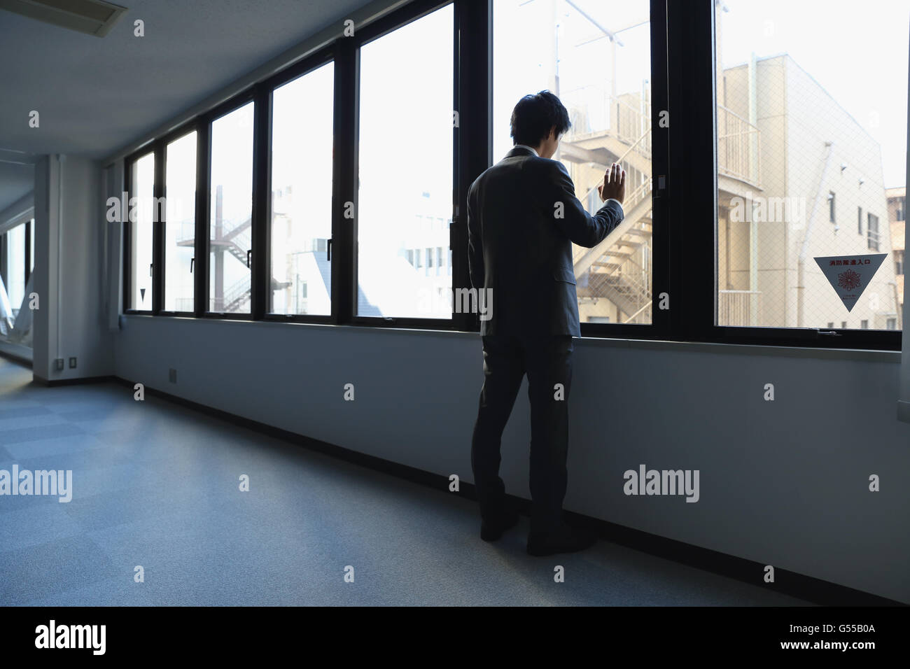 Japanese businessman looking out of the window in empty office Stock Photo