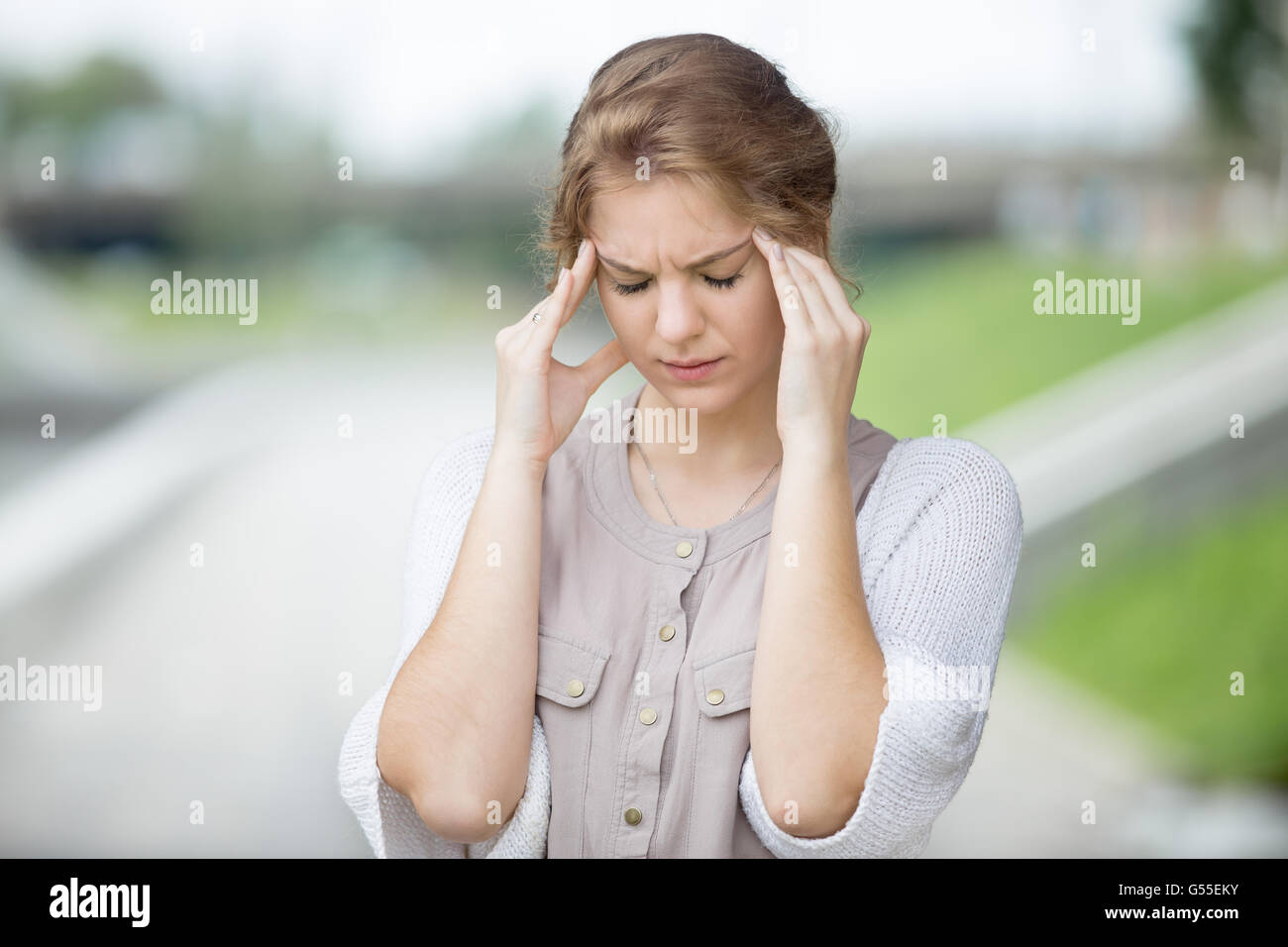 Portrait of stressed beautiful woman walking on the street and holding her head with hands trying to remember something Stock Photo