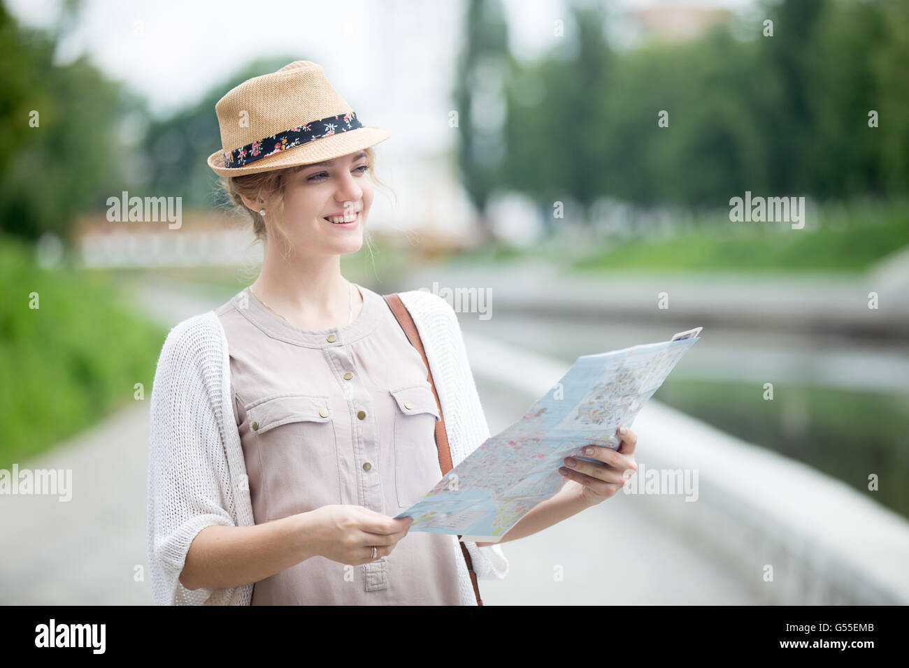Portrait of happy beautiful casual woman traveler searching direction on location map. Young traveling female standing Stock Photo