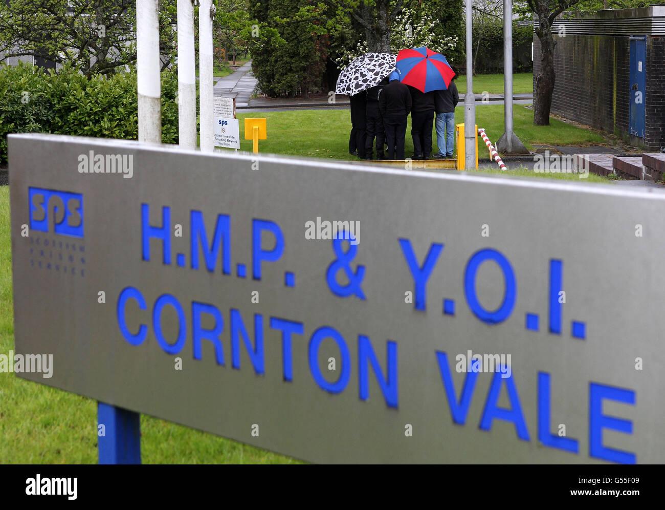 Prison Wardens huddle under umbrellas as they picket the entrance to