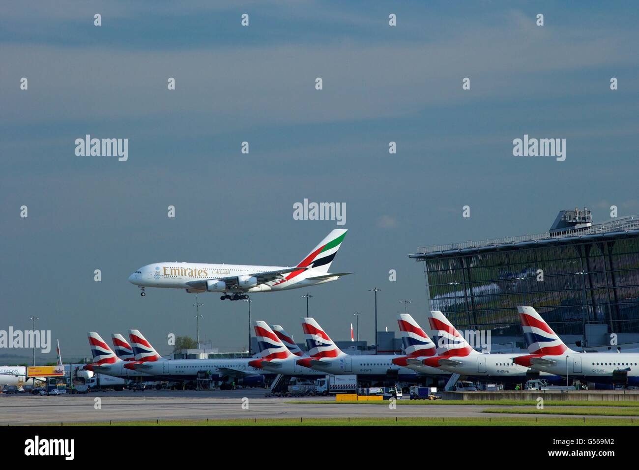 Emirates flight landing at Heathrow Airport with Terminal 5 behind, London, England, UK, GB, Stock Photo