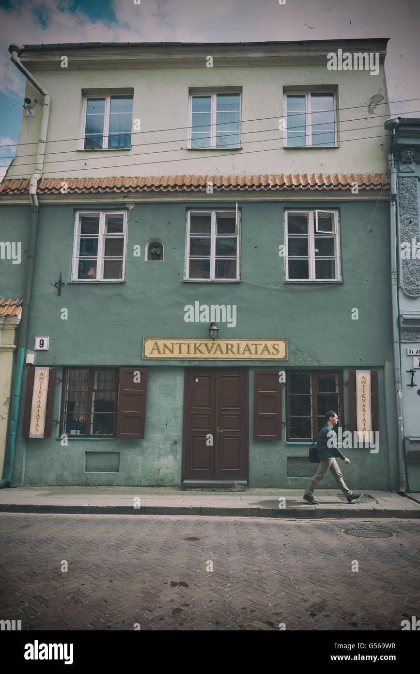 VILNIUS, LITHUANIA - JUNE 8, 2016: An unidentified man walks in front of an antiquarian shop. vintage processing Stock Photo
