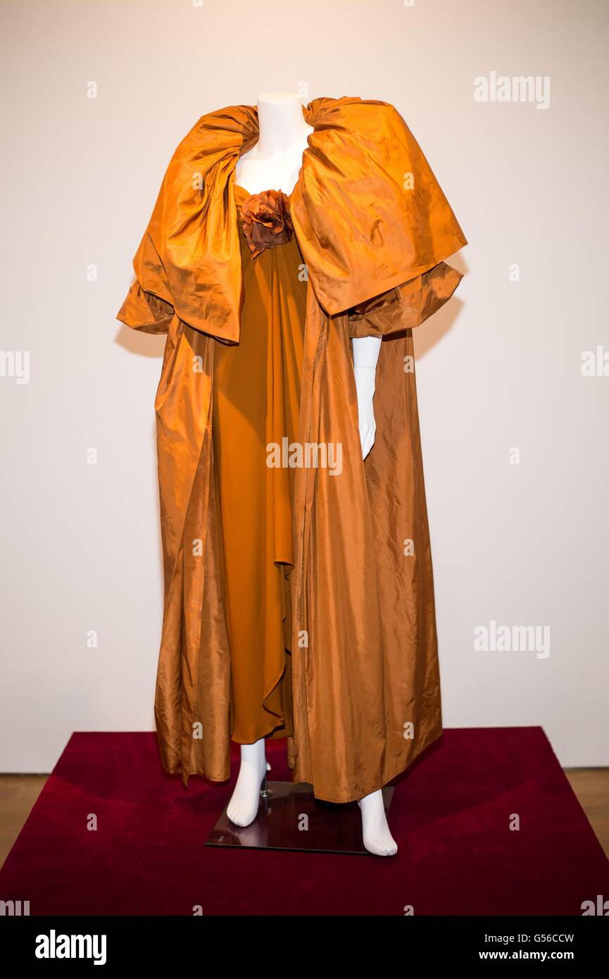 New York, NY, USA. 19th June, 2016. AN OCHRE EVENING ENSEMBLE Comprising a sleeveless dress with sweetheart neck centered by a flower, with asymmetrical hemline and a long matching dress coat with full cape sleeves, the dress and coat with Oscar de la Renta labels; together with a similar ochre wrap applied with leather and sequin embellishments and a floral green silk and velvet wrap inside for Collection of Joan Rivers Press Preview, Christie's Auction House, New York, NY June 19, 2016. Credit:  Steven Ferdman/Everett Collection/Alamy Live News Stock Photo