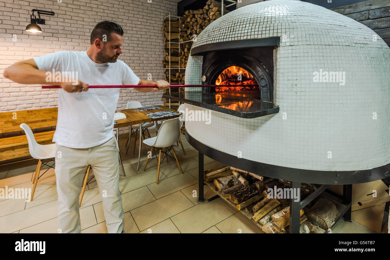 young hipster chef works in pizza restaurant, traditional wood fired stove  Stock Photo - Alamy