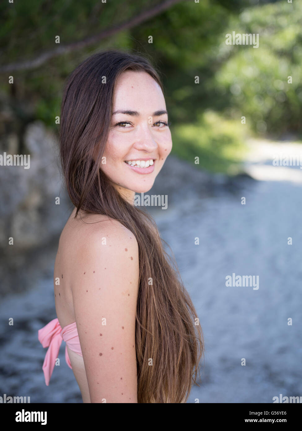 Young beautiful mixed race woman on the beach in bikini smiling Stock Photo