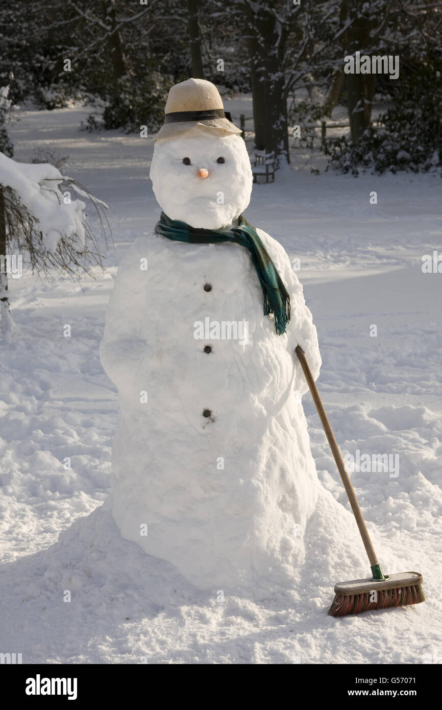 Snowman holding broom in snow covered garden, England, January Stock Photo