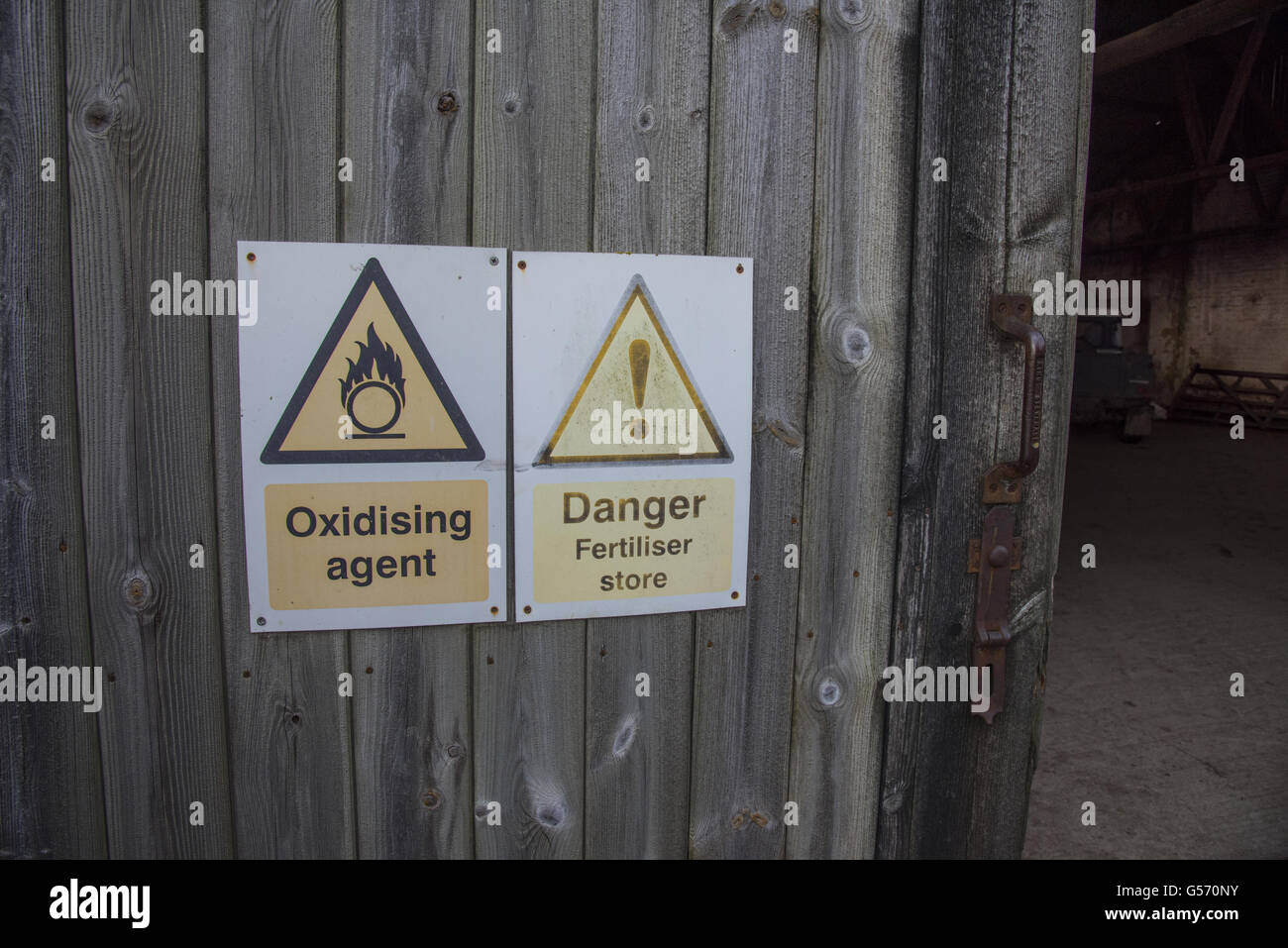 'Oxidising agent' and 'Danger Fertiliser store' warning signs on farm barn door, North Yorkshire, England, January Stock Photo