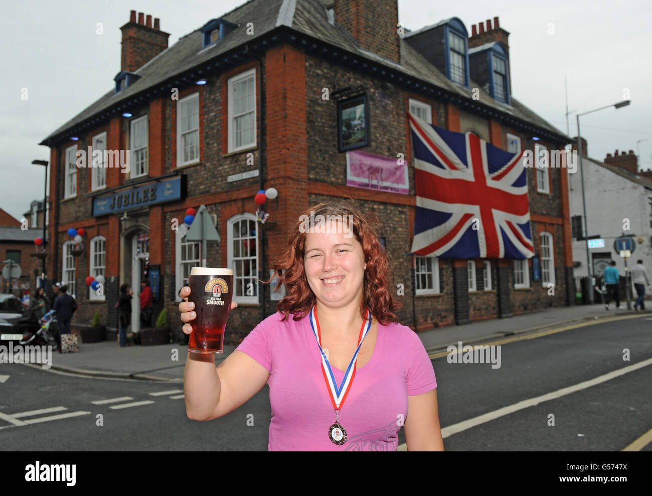 Landlady Kelly Bailey raises a pint of beer outside her pub The Jubilee in York after holding a street party today. Stock Photo