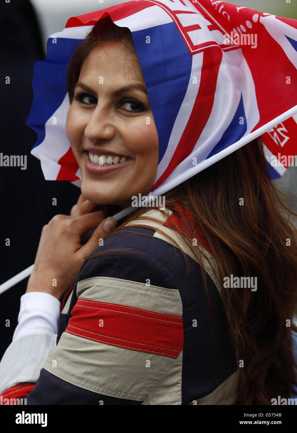 Rashmi Gill from London uses her Union Flag to protect her from the rain on Tower Bridge on the River Thames, London, ahead of the Diamond Jubilee river pageant. Stock Photo