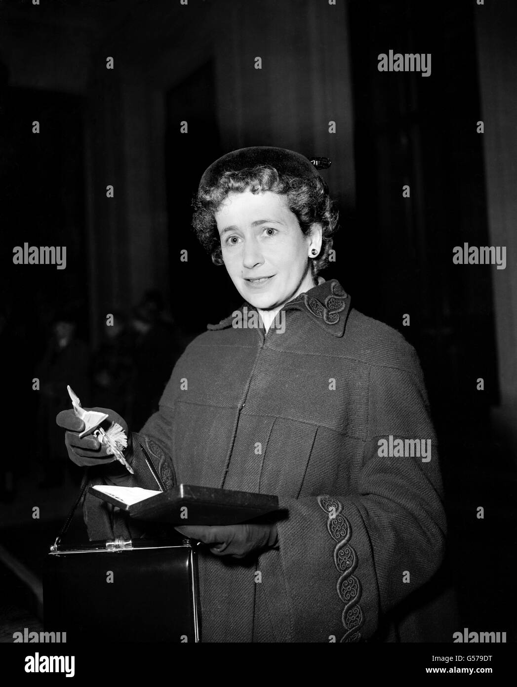 Actress Peggy Ashcroft, viewing the insignia of Commander of the Order of the British Empire which she had just received from the Duke of Gloucester at the Investiture at Buckingham Palace, London. Stock Photo