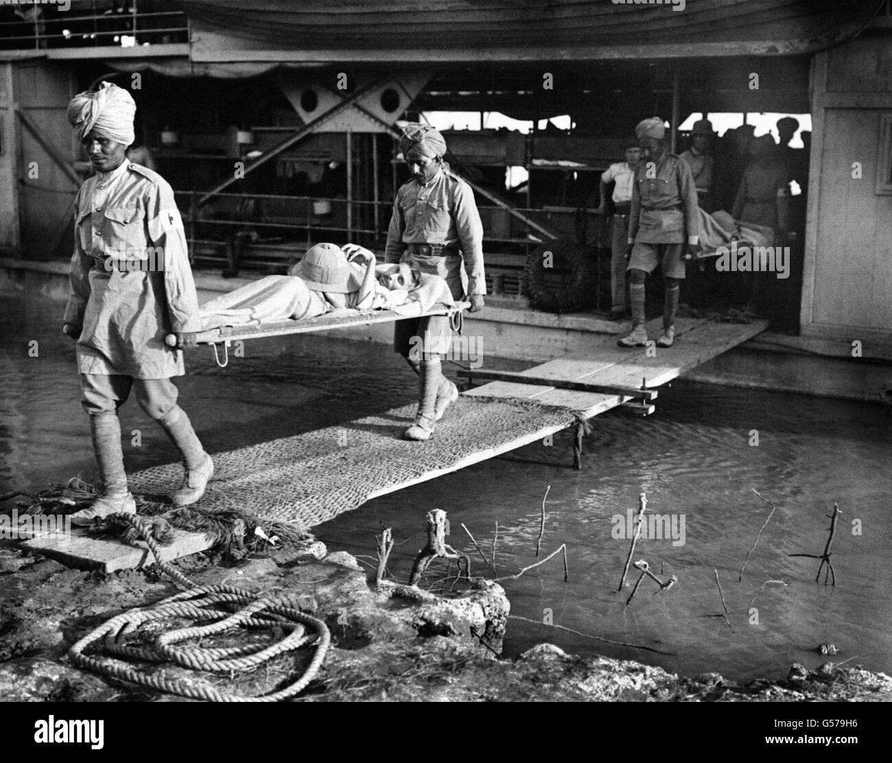 A British casualty being brought down the gangway from a steamer by Indian Army orderlies at Falariyeh, Mesopotamia. The Indian Expeditionary Force, consisting of both British and Indian units, advanced along the Tigris towards Baghdad in Summer 1915. Stock Photo