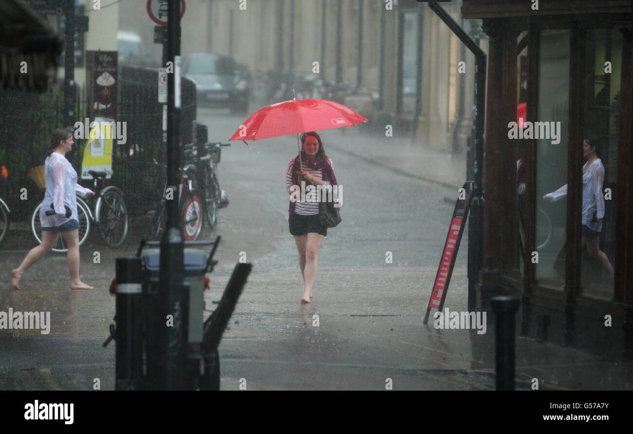 A young woman holds an umbrella after being caught in a thunder storm in Oxford city centre. Stock Photo