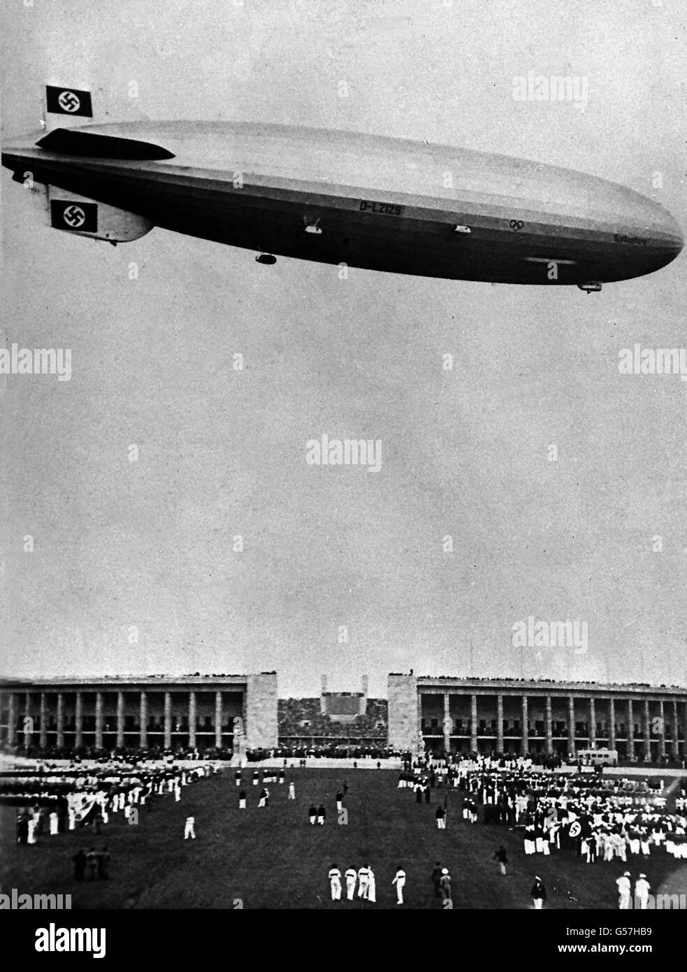 HINDENBURG: The German airship 'Hindenburg', sporting swastika flags on her tail fins, flying over the 1936 Berlin Olympic Games. On May 6th 1937 the airship exploded in a ball of fire as she came in to land in New Jersey, USA. At least 33 passengers and crew were killed. Stock Photo