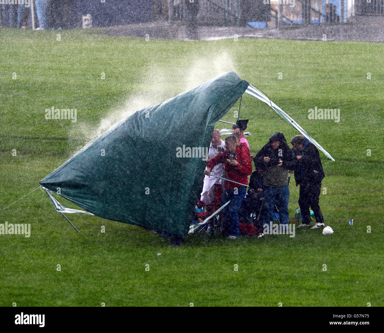 A short rain storm sweeps across the Knavesmire blowing this tent away as  Racegoers try to keep dry on Mid Summer Raceday during the June Meeting at  York Racecourse, York Stock Photo -
