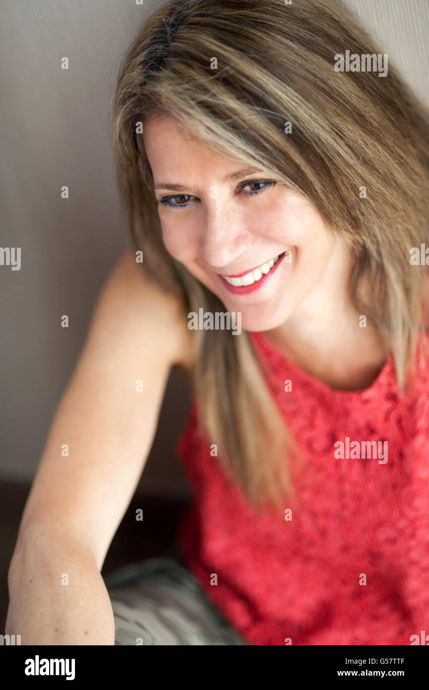 Close up attractive blond 50 year old woman looking away from the camera with toothy smile. Stock Photo