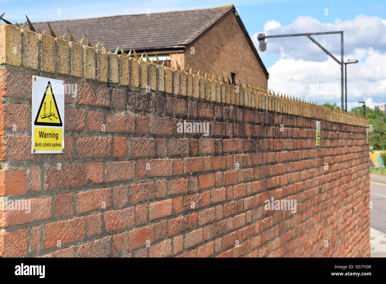 Brick Wall with security climb spikes and warning sign Stock Photo Alamy